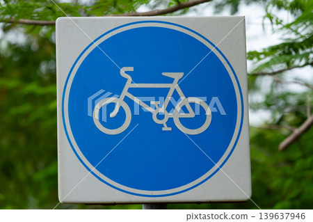 Bicycle road sign on white square sign with blue circle in green outdoor background Bicycle road sign on white square sign with blue circle in green outdoor background 139637946