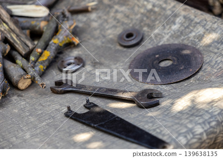 An old metal wrench rests beside grinder attachments on a textured wooden surface to symbolize manual labor, hardware repair, professional workshop craftsmanship, and industrial construction An old metal wrench rests beside grinder attachments on a textured wooden surface to symbolize manual labor, hardware repair, professional workshop craftsmanship, and industrial construction 139638135