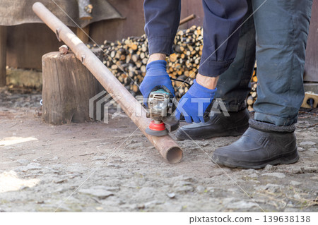 A professional construction worker uses a handheld electric angle grinder to smooth and polish a rusted metal pipe, showcasing industrial maintenance, manual labor, and expert metalwork skill A professional construction worker uses a handheld electric angle grinder to smooth and polish a rusted metal pipe, showcasing industrial maintenance, manual labor, and expert metalwork skill 139638138