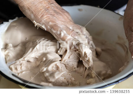 Elderly person mixing fresh yeast starter in a bowl, capturing the authentic process of traditional bread making and natural fermentation techniques for artisanal bakery production Elderly person mixing fresh yeast starter in a bowl, capturing the authentic process of traditional bread making and natural fermentation techniques for artisanal bakery production 139638255