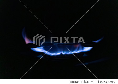 Blue gas flame burning on a kitchen stove burner in the dark, illustrating efficient energy consumption, modern cooking appliances, and domestic heat for preparing daily meals Blue gas flame burning on a kitchen stove burner in the dark, illustrating efficient energy consumption, modern cooking appliances, and domestic heat for preparing daily meals 139638269