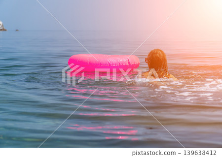 Swimming ocean vacation woman with pink inflatable ring floating peacefully under sunny summer sky Swimming ocean vacation woman with pink inflatable ring floating peacefully under sunny summer sky 139638412