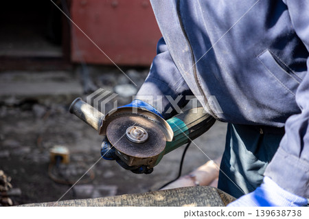 A professional industrial worker uses a powerful angle grinder to cut metal in a workshop while emphasizing precision craftsmanship, hardware maintenance, and essential construction safety tasks A professional industrial worker uses a powerful angle grinder to cut metal in a workshop while emphasizing precision craftsmanship, hardware maintenance, and essential construction safety tasks 139638738