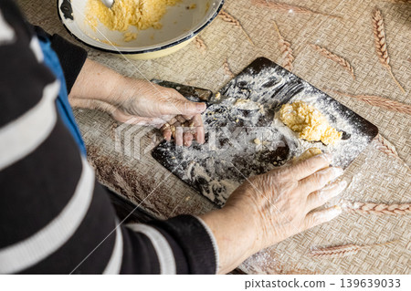 An elderly person shapes soft cottage cheese syrniki on a floured wooden board, embodying traditional home cooking, culinary heritage, and the careful preparation of healthy breakfast meals An elderly person shapes soft cottage cheese syrniki on a floured wooden board, embodying traditional home cooking, culinary heritage, and the careful preparation of healthy breakfast meals 139639033