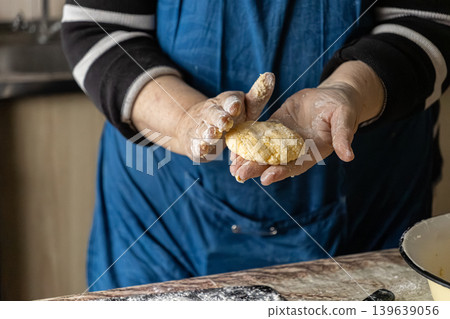 Woman shaping cottage cheese pancakes with floury hands, preparing traditional syrniki for a healthy home cooked breakfast in a rustic kitchen setting, capturing culinary arts and tradition Woman shaping cottage cheese pancakes with floury hands, preparing traditional syrniki for a healthy home cooked breakfast in a rustic kitchen setting, capturing culinary arts and tradition 139639056