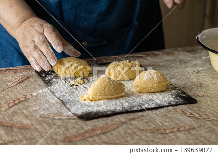 Elderly hands carefully shape fresh cottage cheese pancakes on a floured wooden surface, highlighting traditional homemade cooking, artisanal culinary skills, and a rustic kitchen atmosphere Elderly hands carefully shape fresh cottage cheese pancakes on a floured wooden surface, highlighting traditional homemade cooking, artisanal culinary skills, and a rustic kitchen atmosphere 139639072