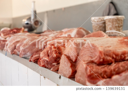 Fresh raw pork meat cuts are arranged on a butcher shop counter to represent high quality protein, traditional food preparation, culinary ingredients, and the local meat trade industry Fresh raw pork meat cuts are arranged on a butcher shop counter to represent high quality protein, traditional food preparation, culinary ingredients, and the local meat trade industry 139639131