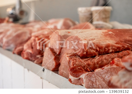Fresh raw pork meat cuts displayed on a stainless steel counter in a butcher shop, representing high quality culinary supplies, traditional food processing and local farm to market trade Fresh raw pork meat cuts displayed on a stainless steel counter in a butcher shop, representing high quality culinary supplies, traditional food processing and local farm to market trade 139639132