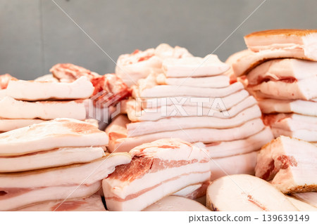 Raw pork fat pieces stacked on a market counter, representing fresh butchery products for cooking traditional savory dishes and culinary preparation in a commercial food retail environment Raw pork fat pieces stacked on a market counter, representing fresh butchery products for cooking traditional savory dishes and culinary preparation in a commercial food retail environment 139639149