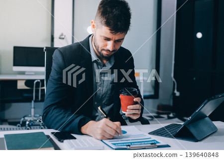 Tired worker. A tired businessman works in the evening. A man in office clothes is holding his temples. Problems in business. The businessman is trying to solve the problems that have arisen. Tired worker. A tired businessman works in the evening. A man in office clothes is holding his temples. Problems in business. The businessman is trying to solve the problems that have arisen. 139640848