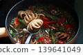 cooking spicy stir-fried baby octopus with basil and chili in a hot pan with steam, high-angle view of delicious Asian seafood cuisine 139641049