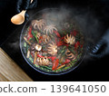 chef in black gloves cooking spicy stir-fried baby octopus with basil and chili in a hot pan with steam, high-angle view of delicious Asian seafood cuisine 139641050
