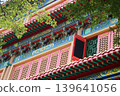 traditional Chinese temple architecture featuring ornate roof patterns, red windows, and colorful decorations against a clear sky with copy space for design. 139641056
