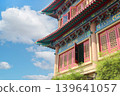 traditional Chinese temple architecture featuring ornate roof patterns, red windows, and colorful decorations against a clear sky with copy space for design. 139641057