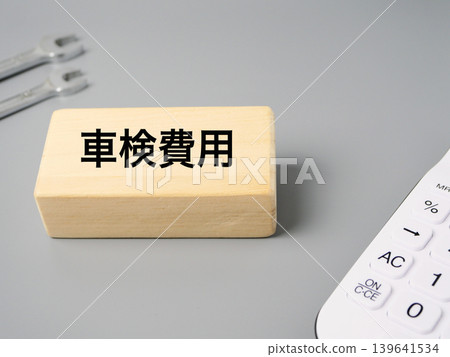 Simple design featuring tools, a calculator, and wooden blocks to represent car inspection costs, against a gray background. Simple design featuring tools, a calculator, and wooden blocks to represent car inspection costs, against a gray background. 139641534