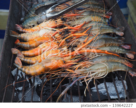 Grilled shrimp prawn seafood barbecue fresh shellfish closeup on grill with charcoal heat outdoor cooking scene Grilled shrimp prawn seafood barbecue fresh shellfish closeup on grill with charcoal heat outdoor cooking scene 139642227