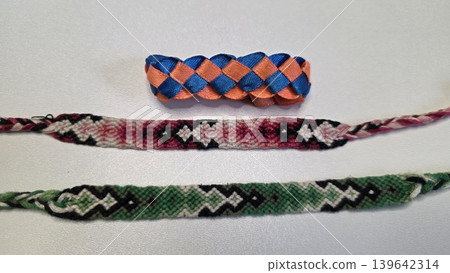 Set of three colorful handmade woven friendship bracelets made of threads and ribbons isolated on white background. Traditional diy textile craft hobby and summer youth accessories. Set of three colorful handmade woven friendship bracelets made of threads and ribbons isolated on white background. Traditional diy textile craft hobby and summer youth accessories. 139642314