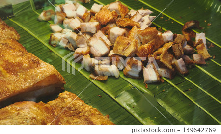 Crispy pork belly chopped into pieces served on fresh banana leaf, Thai street food style. Crispy pork belly chopped into pieces served on fresh banana leaf, Thai street food style. 139642769