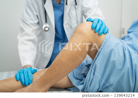 Doctor checking Asian elderly woman patient with scar knee replacement surgery in hospital. 139643214