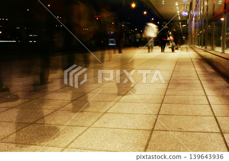 a group of people walking along the sidewalk promenade long exposure at night a group of people walking along the sidewalk promenade long exposure at night 139643936