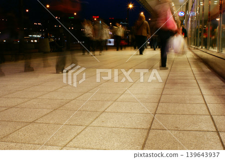 a group of people walking along the sidewalk promenade long exposure at night a group of people walking along the sidewalk promenade long exposure at night 139643937