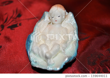 a small figurine of little Jesus Christ on a red background a small figurine of little Jesus Christ on a red background 139644011