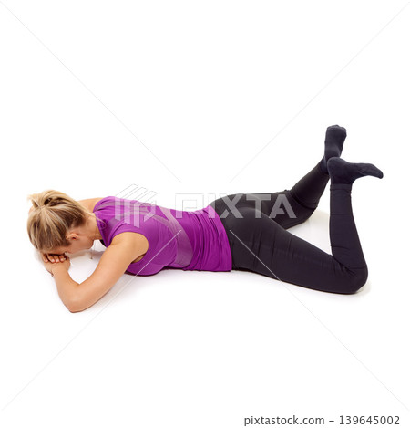 Woman, stretching and pilates for thighs, hips and glutes on floor in white background of studio. Yoga, exercise and person workout for legs on ground with feet raised in the air in pose for fitness Woman, stretching and pilates for thighs, hips and glutes on floor in white background of studio. Yoga, exercise and person workout for legs on ground with feet raised in the air in pose for fitness 139645002