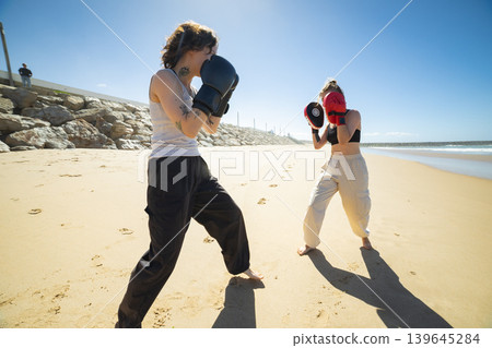 Women training boxing with focus mitts on beach 139645284