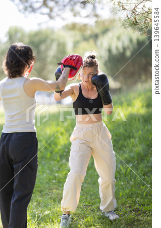 Women training boxing outdoors for strength and fitness Women training boxing outdoors for strength and fitness 139645584