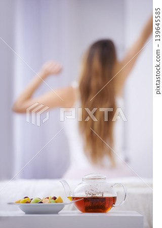 Breakfast, tea and woman in bedroom, stretching with fruit salad for good diet and nutrition. Healthy food, herbal drink and wake up, girl on bed getting ready to start day in home or hotel from back Breakfast, tea and woman in bedroom, stretching with fruit salad for good diet and nutrition. Healthy food, herbal drink and wake up, girl on bed getting ready to start day in home or hotel from back 139645585