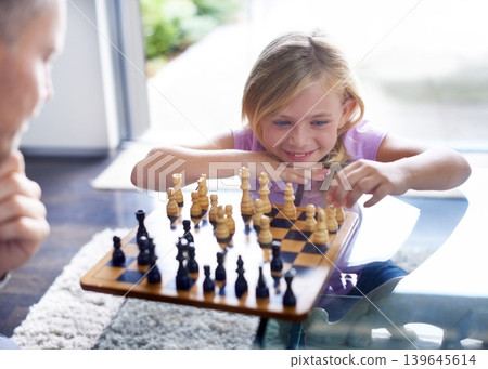 Smile, kid and father play chess in home, family bonding together or development. Happy girl, man and board game of strategy, challenge or entertainment of young child in competition match in house Smile, kid and father play chess in home, family bonding together or development. Happy girl, man and board game of strategy, challenge or entertainment of young child in competition match in house 139645614