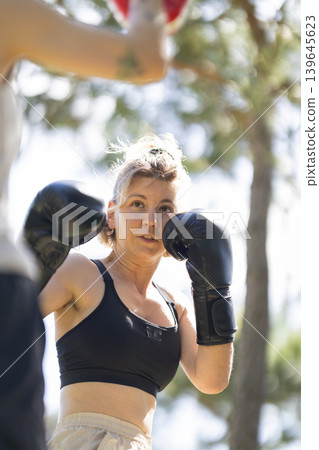 Woman training boxing outdoors, building strength and determination Woman training boxing outdoors, building strength and determination 139645623