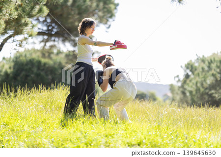 Two women training kickboxing with focus mitts outdoors Two women training kickboxing with focus mitts outdoors 139645630