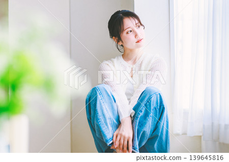 A young woman in jeans sitting on a chair A young woman in jeans sitting on a chair 139645816