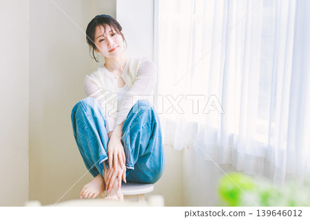 A young woman in jeans sitting on a chair A young woman in jeans sitting on a chair 139646012