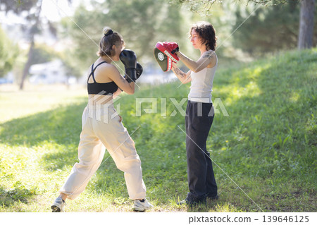 Women boxing training outdoors hitting focus mitt Women boxing training outdoors hitting focus mitt 139646125