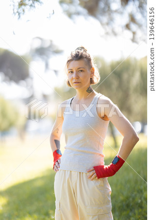 Determined young woman standing with boxing wraps outdoors Determined young woman standing with boxing wraps outdoors 139646156