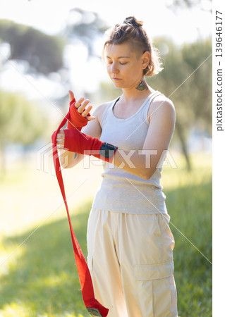 Woman wrapping hands preparing for combat sport training Woman wrapping hands preparing for combat sport training 139646177