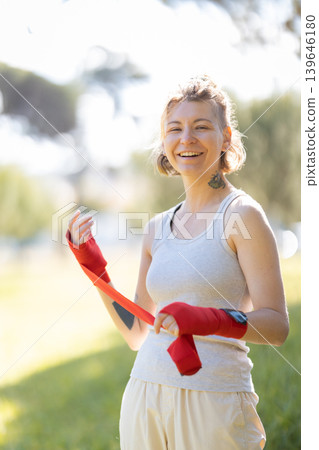 Young woman wrapping hands, preparing for combat sport Young woman wrapping hands, preparing for combat sport 139646180