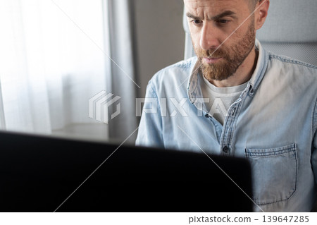 Focused businessman working on computer in home office Focused businessman working on computer in home office 139647285