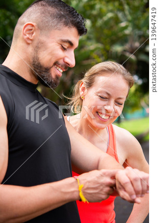 Personal trainer checking fitness smartwatch with mature woman outdoors Personal trainer checking fitness smartwatch with mature woman outdoors 139647419