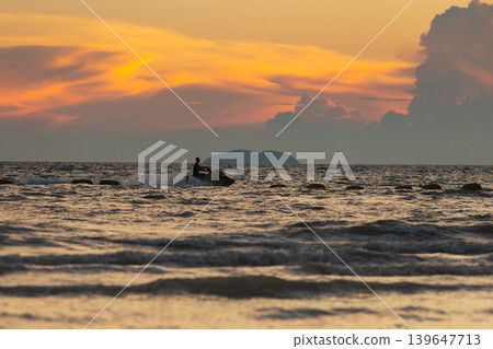 Silhouette of a person riding a jet ski on the ocean during a vibrant sunset Silhouette of a person riding a jet ski on the ocean during a vibrant sunset 139647713