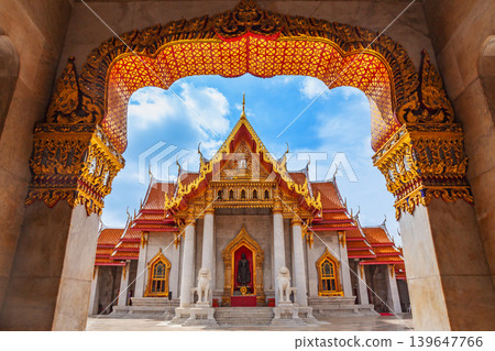 Ornate golden archway frames a majestic Thai temple with intricate architecture Ornate golden archway frames a majestic Thai temple with intricate architecture 139647766