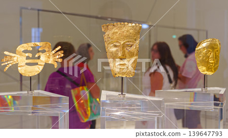 Abu Dhabi, United Arab Emirates - Jan 17 2024, close-up view of the ancient golden masks behind which visitors walk, the background is blurred, on exhibition of Louvre Abu Dhabi, United Arab Emirates Abu Dhabi, United Arab Emirates - Jan 17 2024, close-up view of the ancient golden masks behind which visitors walk, the background is blurred, on exhibition of Louvre Abu Dhabi, United Arab Emirates 139647793