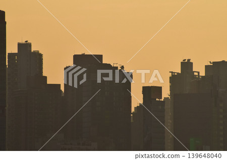 Skyscapers of Hong Kong at the sunset in silhouette. Hong Kong cityscape. Modern Buildings. Building exterior. Travel concept. Background use. Skyscapers of Hong Kong at the sunset in silhouette. Hong Kong cityscape. Modern Buildings. Building exterior. Travel concept. Background use. 139648040
