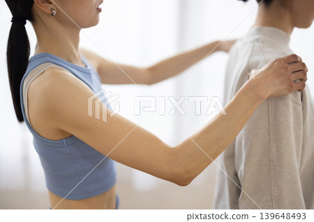 A yoga instructor checking a woman's posture. A yoga instructor checking a woman's posture. 139648493