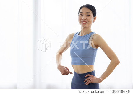 一位身穿瑜珈服的日本女子麵帶微笑，指著自己的腰。 139648686