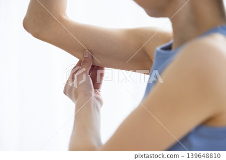 Japanese woman in yoga wear pinching her upper arm Japanese woman in yoga wear pinching her upper arm 139648810