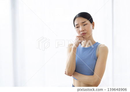 一位神情憂慮的日本女子站在明亮的窗邊。 139648906
