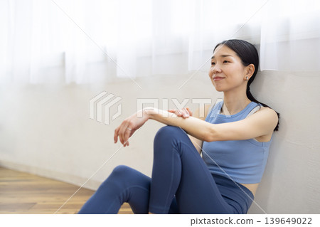 一位身穿瑜珈服的日本女性坐在地板上微笑。 139649022